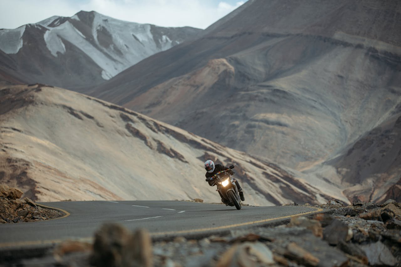 contact-img Motorcyclist navigating a winding road amid the stunning landscape of the Ladakh mountains in India.
